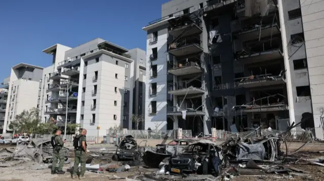 Israeli Home Front Command team members work at the site where Iranian ballistic missiles struck residential buildings in Beersheba