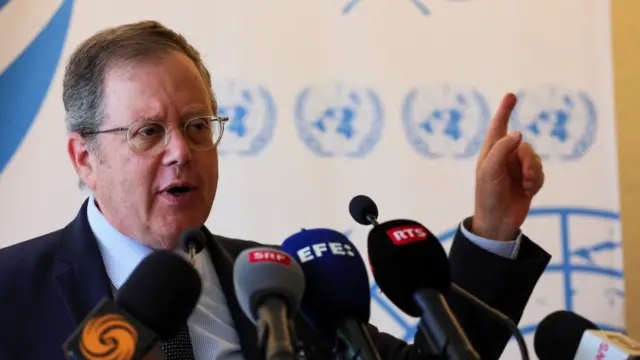 Daniel Meron speaks to microphones in front of a backdrop bearing the UN logo