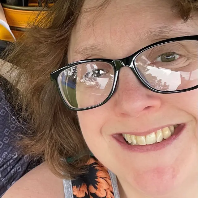 A photo of Zoe Mead, she is smiling and wearing glasses