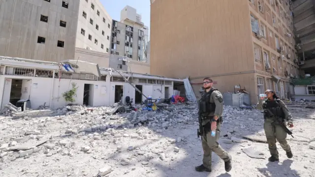 Israeli security personnel walk near an Israeli hospital hit by an Iranian missile on Thursday.