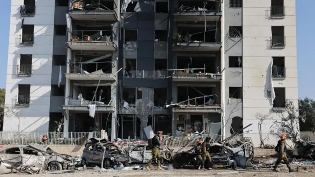 Israeli troops assess the damage at a multi-storey block in Beersheba