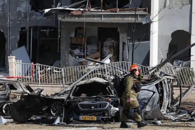Israeli Home Front Command team members walk at the site where Iranian ballistic missiles struck residential buildings in Beersheva