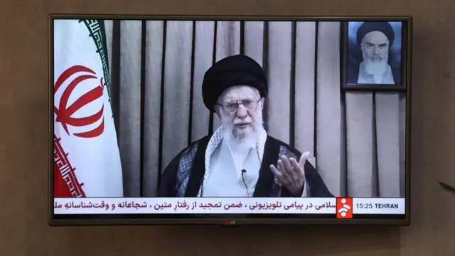 A TV playing an Iranian news channel hangs on a wall.