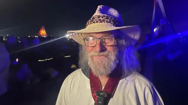 Rollo Maughfling, the archdruid of Stonehenge and Britain. He is lit by TV lights and is smiling into the camera.