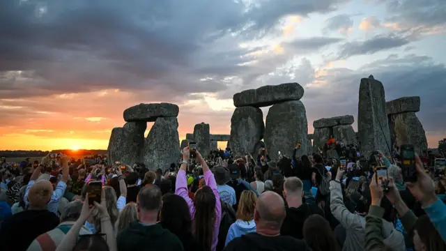 Hundreds of people hold up phones to take pictures of Stonehenge