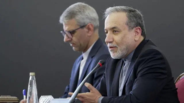 Iran's foreign minister sits behind a microphone.