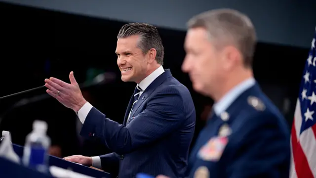 Pete Hegseth speaks behind a podium.