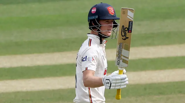 Charlie Allison of Essex raises his bat to celebrate reaching his fifty