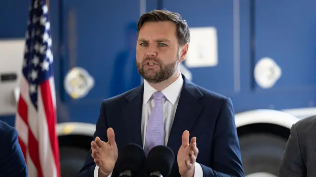 Vance speaks behind a podium wearing a suit.