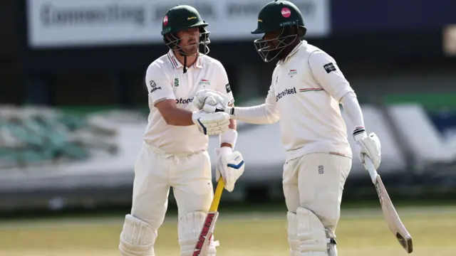 Rehan Ahmed (right) is congratulated by Lewis Hill on reaching 50