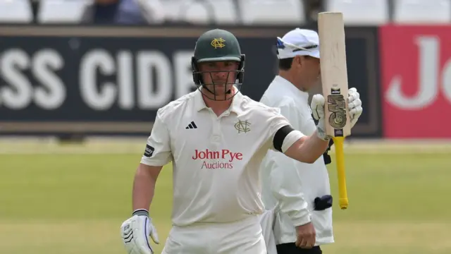 Dillon Pennington raises his bat having reached 50
