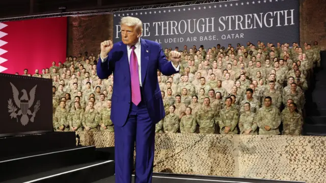 Trump holds up a fist as he walks on stage in front of crowds of US service personnel