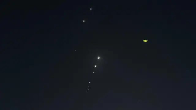 Flashes of light can be seen high in the sky - they appear as small white dots against the darkness