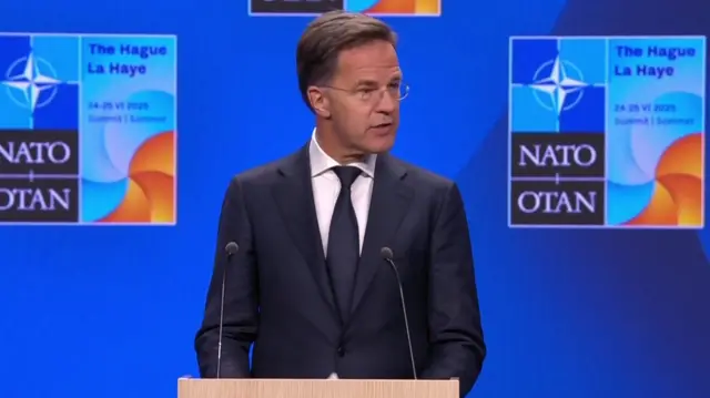 Nato Secretary General Mark Rutte speaking at a news conference in The Hague. He is wearing a suit and standing at a podium