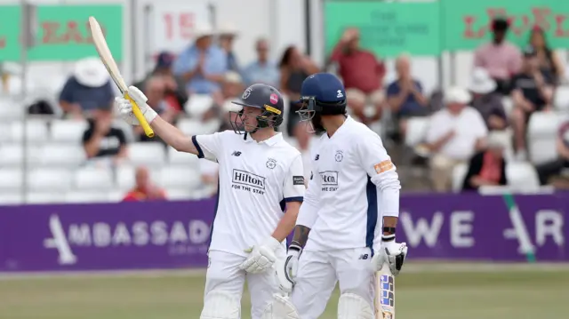 Fletcha Middleton of Hampshire raises his bat to celebrate reaching his fifty
