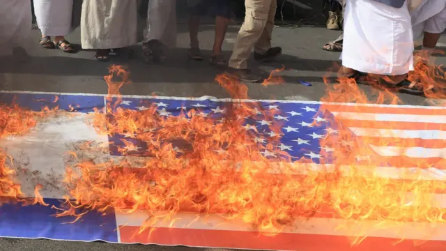 Houthi supporters burn a US flag during a protest against the Israeli airstrikes on Iran, in Sana'a, Yemen