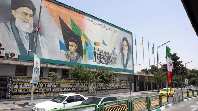 Cars in Tehran drive past large posters of Iran's supreme leader and former supreme leader Ayatollah Ruhollah Khomeini