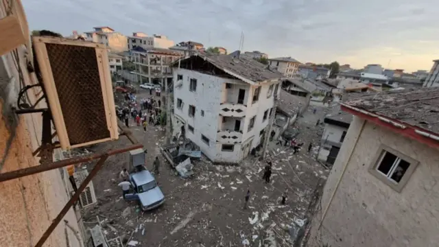 Debris is scattered across a built up suburb with the windows blown out in many of the buildings