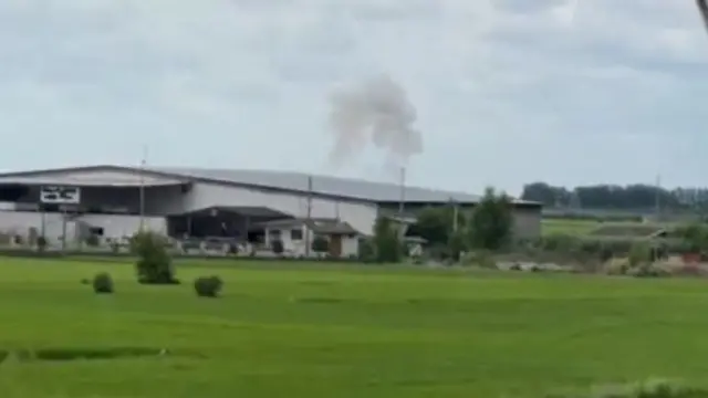 Smoke rising from behind a warehouse which we could locate on maps due to its distinctive roof