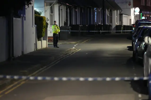 A police officer in the distance guarding a section of road.