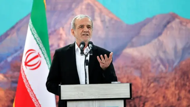 Iran's President Masoud Pezeshkian speaking in front of a lectern, with the Iran flag and mountain imagery in the background