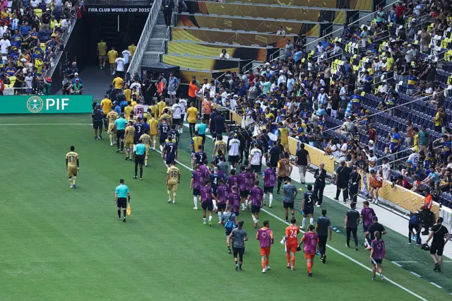 Boca Juniors and Auckland City players make their way off the field due to a weather delay