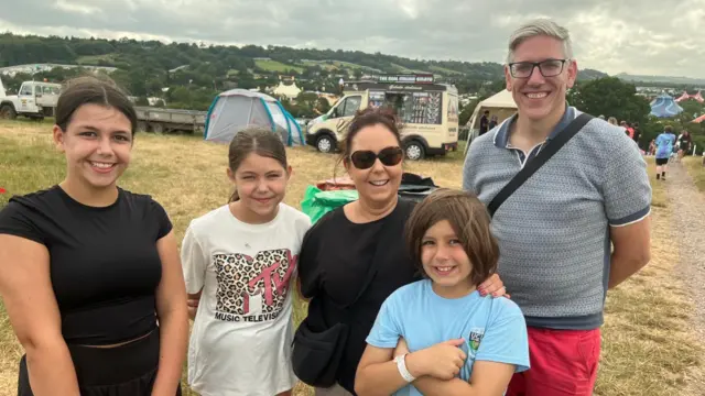 Thomas and Liz with their children Tom, Katie and Molly. The family are all standing in a field with an ice cream van behind them.