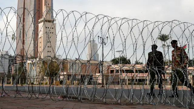 Security officers walk near a razor wire erected to block access to the Parliament buildings