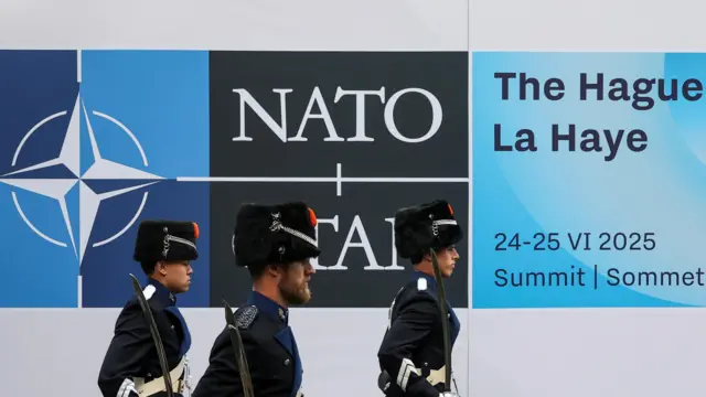 Military personnel at Nato summit in the Hague, walking past sign