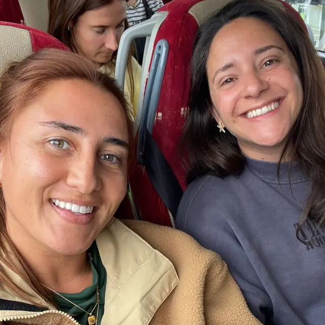 Issy and Alice on a coach smiling into camera