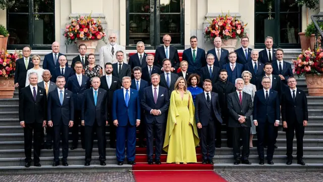 Leaders of Nato member states pose for family photo in The Hague. Front centre on a red carpet, are King William-Alexander (L) and Queen Maxima of The Netherlands (R), with Donald Trump to the King's right and Emmanuel Macron to the Queen's left