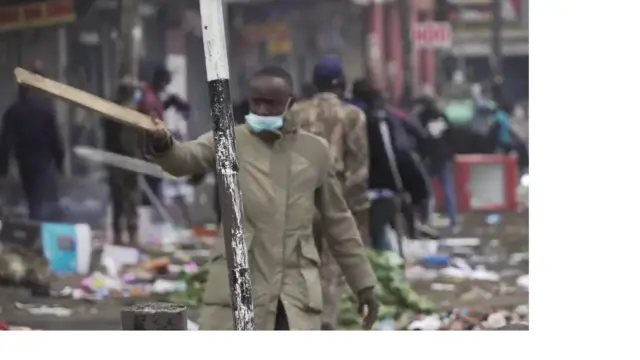 A man with a face mask waving a stick