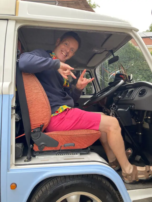 A man sat in the driver seat of a camper van