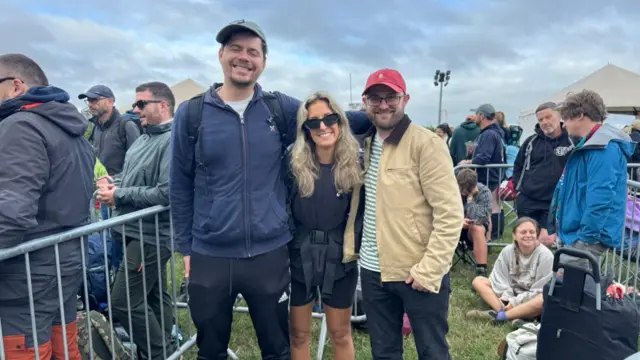 James, Grace and Dan smile for the camera as they queue up.