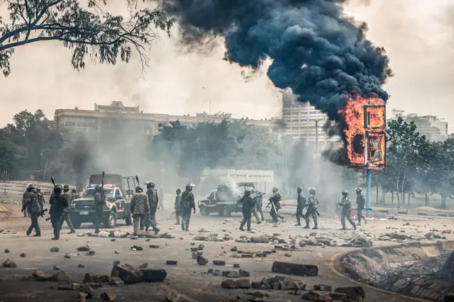 Members of Kenya security forces gather near a burning billboard in downtown Nairobi on June 25, 2025 during a planned day of protest marking the first anniversary of the storming of the parliament.