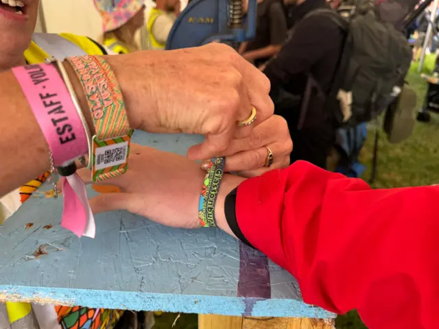 A close up of a multi-coloured wristband being tied around a wrist.
