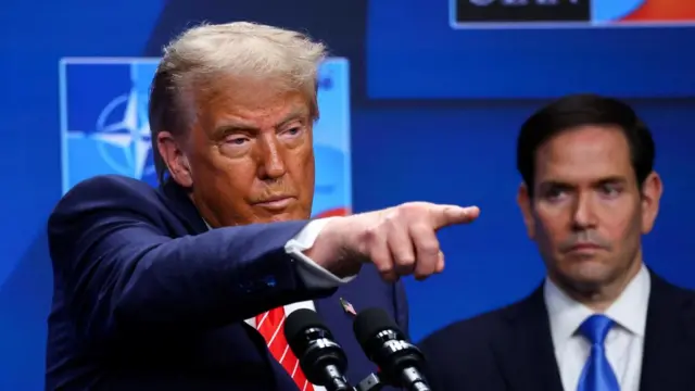 Trump points at reporters during a press conference at the Nato summit. Secretary of State Marco Rubio is in the background.