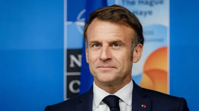 Macron standing in a suit