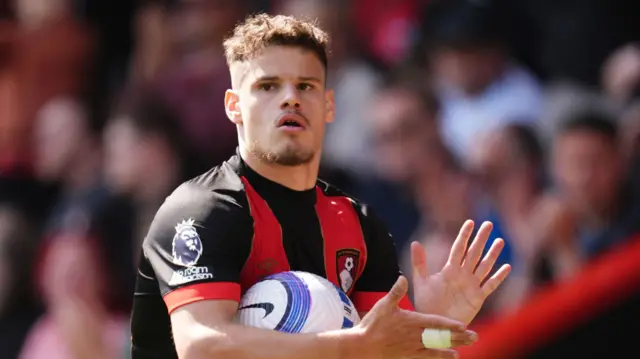 Milos Kerkez holds a football while playing for Bournemouth