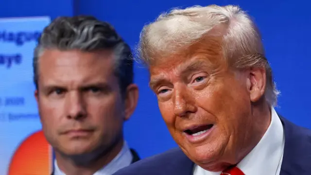 Trump speaks while Hegseth stands behind him