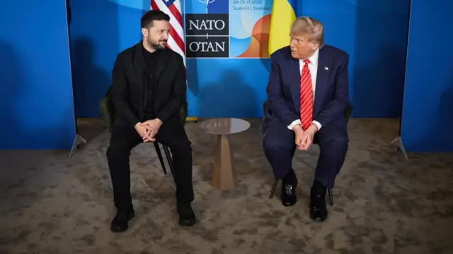 Volodymyr Zelensky and Donald Trump sit next to a table with the Nato sign and an American and a Ukrainian flag behind them
