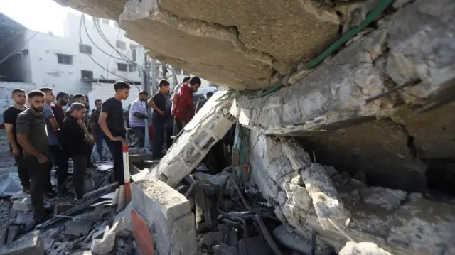 Palestinians search for casualties at the site of an overnight Israeli strike on a fuel station where displaced people shelter, in Gaza City, June 25, 2025