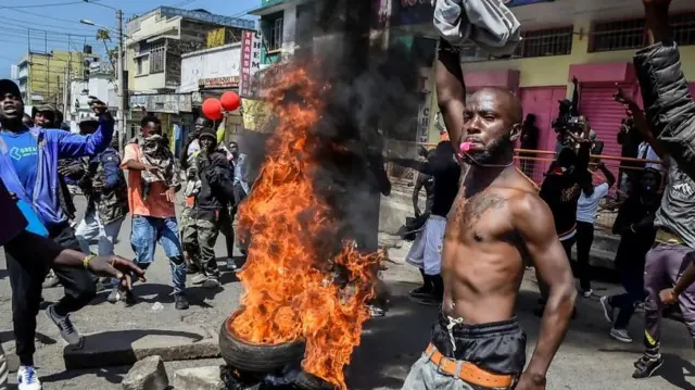 A protester without a shirt around a bonfire