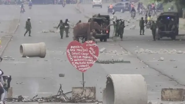 Elephant sculpture in a road surrounded by soldiers and debris