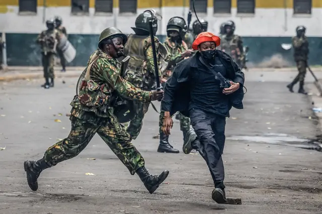 A protester grimace as a member of the Kenyan security forces hits him with a baton in downtown Nairobi on June 25, 2025
