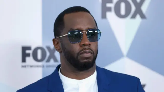 Sean "Diddy" Combs in 2018. He is wearing a blue suit jacket over a white shirt. He is wearing blue-lensed glasses.
