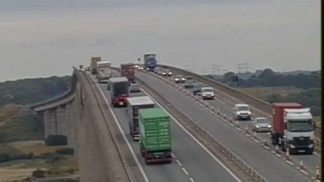 A view over the Orwell Bridge near Ipswich. Drivers move over both carriageways. A lane is closed on the carriageway furthest away from the camera.