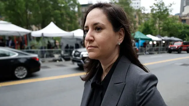 Christy Slavik wears a dark suit and stands outside on a New York street