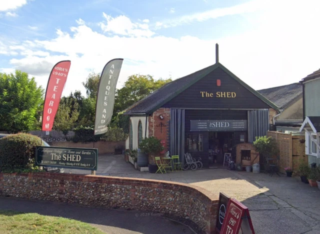 The outside of the Shed in Sproughton. A small building can be seen with tables and chairs outside.