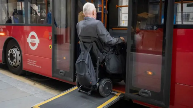 A man in a powered wheelchair getting on a bus